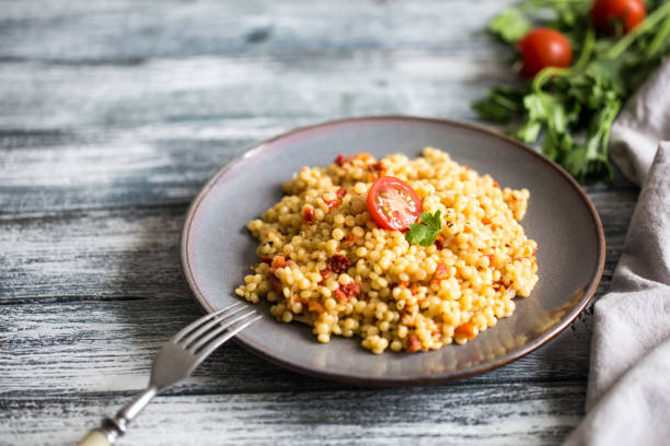 Ptitim or Birdy, Israeli pasta couscous  with tomatoes and herbs stock photo