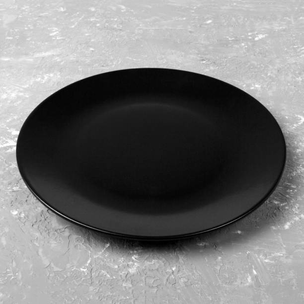 istock Round plate on table. black dish on gray cement background. copy space 1178921056