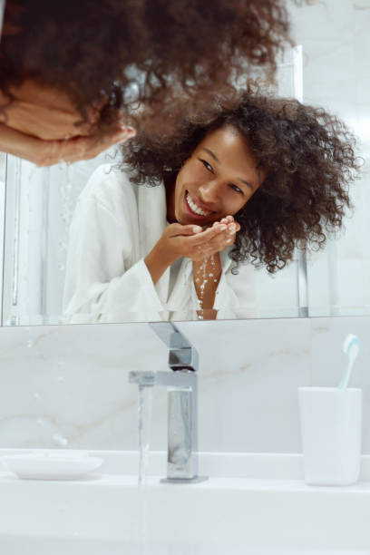 cuidado de la piel. mujer lavando la cara con agua en el lavabo en el baño - human face water washing women fotografías e imágenes de stock