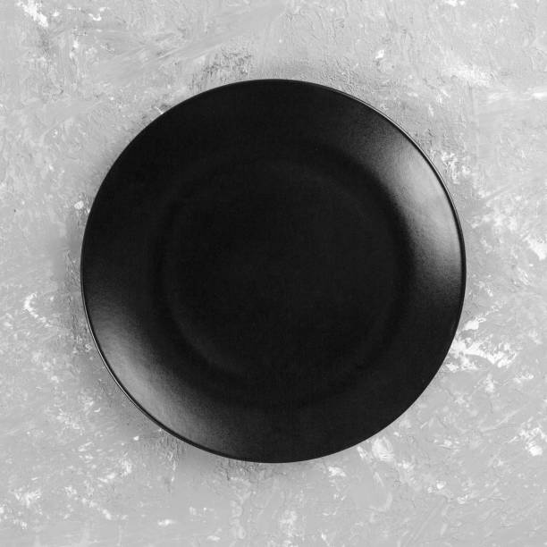 istock Black round plate on gray cement background, top view, copy space 1178922323