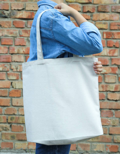 istock Young woman holding tote bag against brick wall, empty space 1178924116