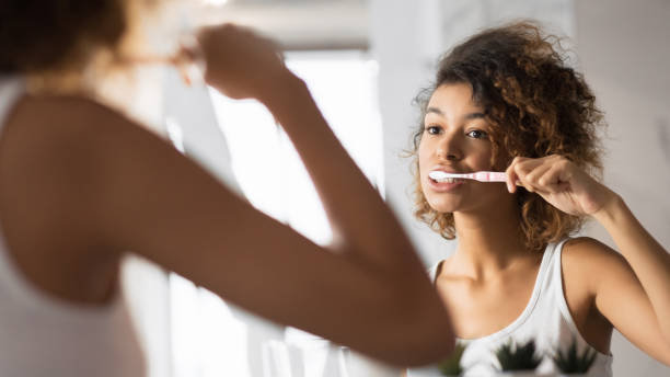 african american girl brushing teeth with toothbrush in bathroom, panorama - brushing teeth women toothbrush brushing imagens e fotografias de stock