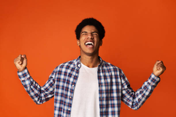 istock African-american guy celebrating victory over orange background 1178925333