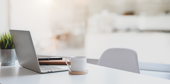 Lugar de trabajo moderno con computadora portátil, taza de café y artículos de oficina photo