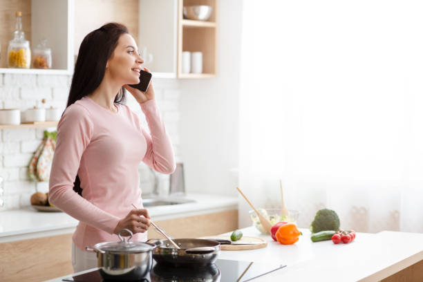 istock Millennial woman talking on phone, preparing lunch at kitchen 1178926480