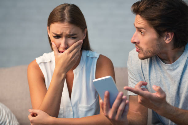 istock Husband Showing Cheating Wife Her Phone Sitting On Sofa Indoor 1178926637