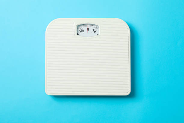 istock White weigh scales on blue background, top view 1178928012