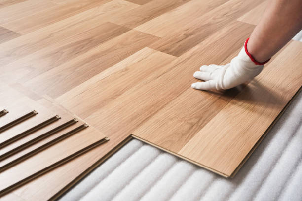 istock Installing laminated floor, detail on man hand in white glove fitting wooden tile, over white foam base layer 1178928362