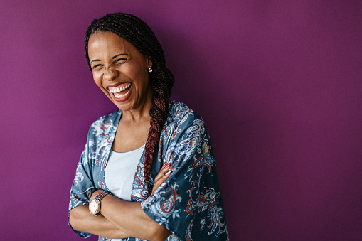 Laughing woman with crossed hands standing on purple background