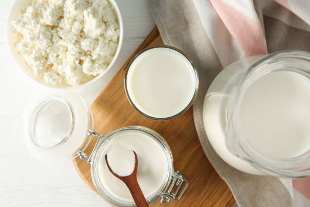 istock Fresh dairy products, board and towel on white wooden table, top view 1178929122