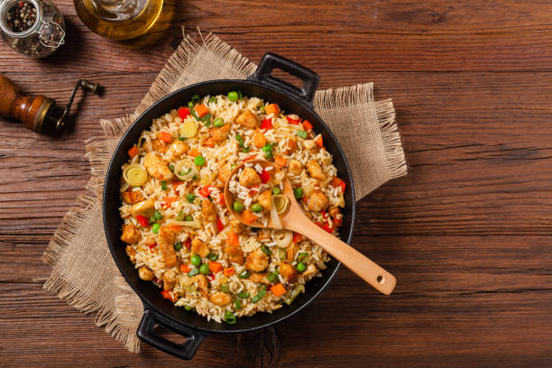 Fried rice with chicken. Prepared and served in a wok. Fried rice with chicken. Prepared and served in a wok. Natural wood in the background. Top view. hot mix plant stock pictures, royalty-free photos & images