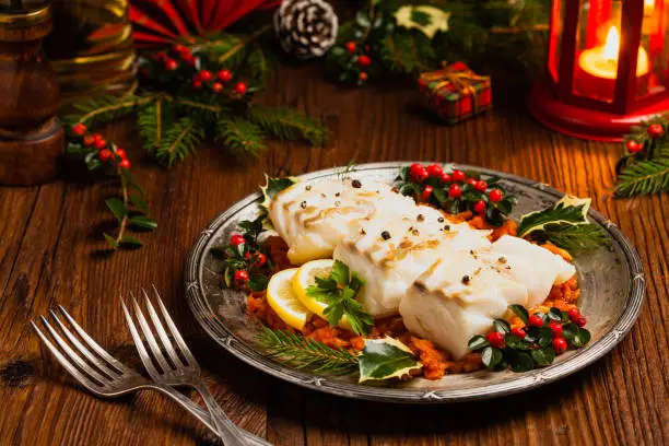 Christmas fish. Roasted cod pieces, served in vegetable sauce. Xmas styling. Front view.