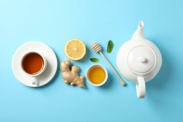 istock Flat lay. Cup of tea, teapot, lemon, ginger, mint, honey and dipper on blue background, copy space 1178930016
