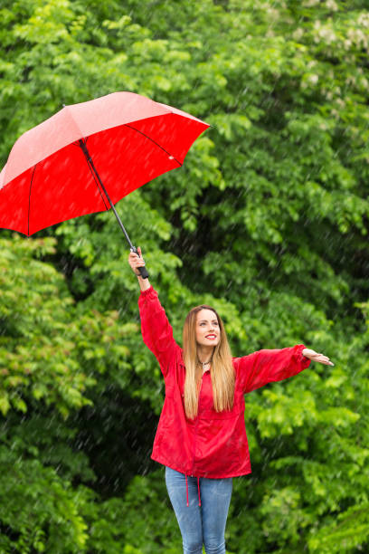 istock Woman with red umbrella having fun in rainy day 1178931999