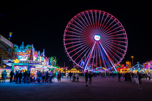 Stuttgart, Germany, October 3, 2019, Many people enjoying colorful big wheel and food offers at canstatter wasen oktoberfest folk festival by night