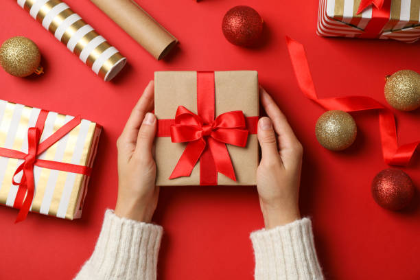 istock Female hands holding present on decorated background, top view 1178940455