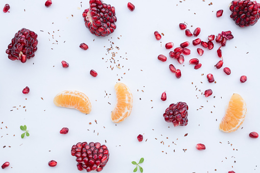 Pomegranate, Orange slices and dry tea leaves on a white background seen from above