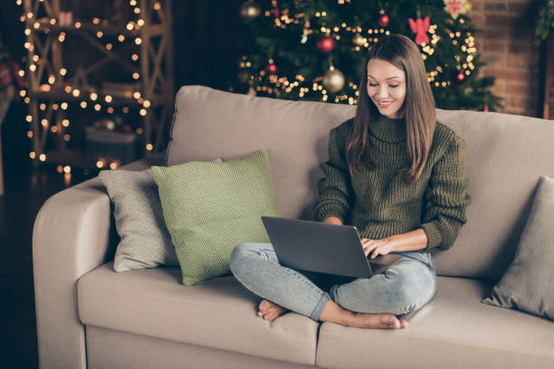 Top above high angle view photo of positive girl wear knitted jumper use laptop search winter shopping discounts text sit divan cross legs in house full of christmas decoration illumination indoors Top above high angle view photo of positive girl wear knitted jumper use laptop, search winter shopping discounts text sit divan cross legs in house full of christmas decoration illumination indoors holiday shopping stock pictures, royalty-free photos & images