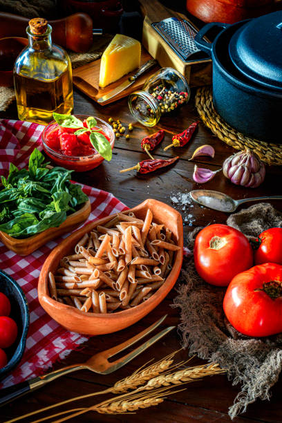 istock Penne pasta and ingredients on rustic pots and wooden table in a kitchen 1178950980
