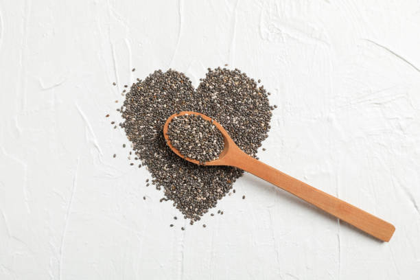 Heart layout of chia and wood spoon on white background, space for text Heart layout of chia and wood spoon on white background, space for text chia seed photos stock pictures, royalty-free photos & images