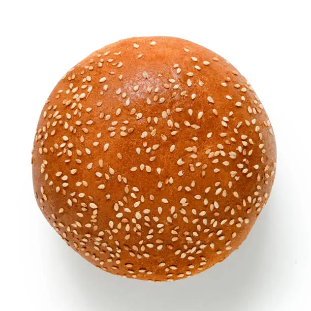 Photo of Sesame seed hamburger bun isolated on white. Top view.