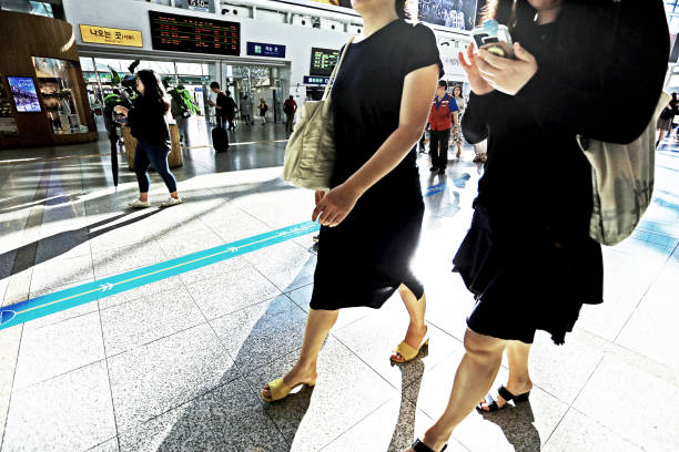 kobiety idące ulicą dworca kolejowego trzymające telefon komórkowy - lee street station zdjęcia i obrazy z banku zdjęć