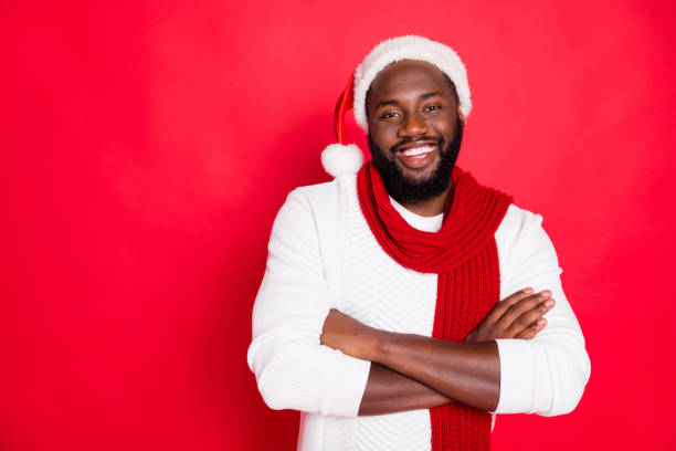 verticale de l'homme américain drôle positif de cheveux drôles croisent sa main prête à célébrer le temps de noel de nouvelle année porter l'écharpe blanche de pull d'isolement au-dessus du fond rouge de couleur - christmas fashion model human arm beautiful photos et images de collection