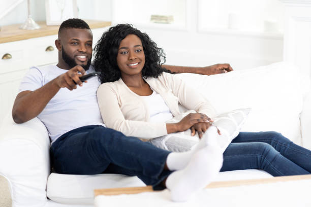 istock Afro couple relaxing on couch at home and watching tv 1178959892