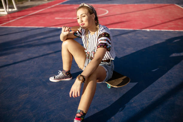 istock Young woman sitting on skateboard and eating ice cream 1178960010
