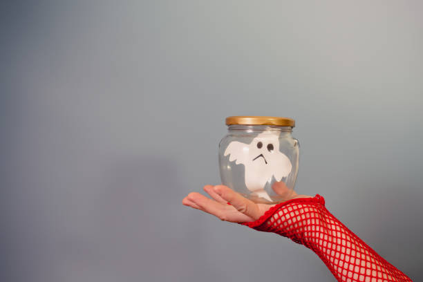 A woman's hand holds a jar with a caught ghost
