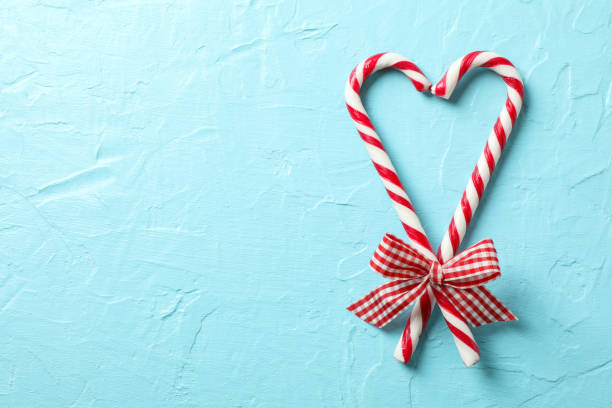 istock Sweet candy canes with bows on blue background, space for text 1178961868
