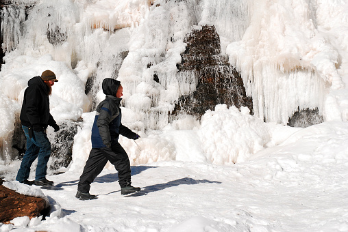 Hunter, NY, USA February 18, 2013 A couple takes a winter's walk past a frozen waterfall in Catskill Park near Hunter, New York