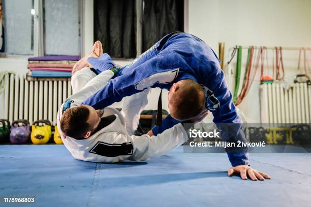 Brazilian Jiu Jitsu Bjj Martial Arts Training Sparring At The Academy Two Fighters Reverse De La Riva Guard Position Drilling Techniques Practicing In A Gi Kimono Stock Photo - Download Image Now