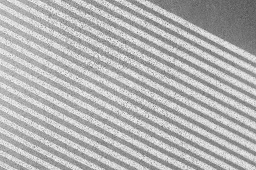 abstract shadow batten of lath and morning light on white concrete wall texture background
