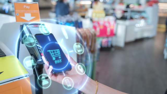 4k resolution Internet of Things and Mobile Payment concept,close up hand holding smart phone with Communication icons.Paying through terminal.Connection and wireless network Technology