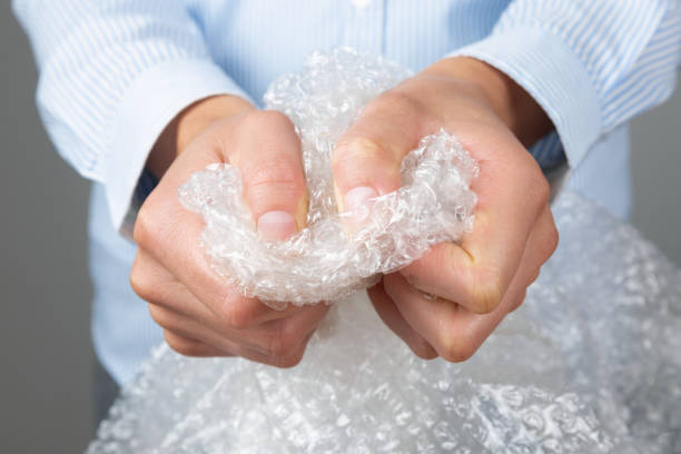 Female hands popping the bubbles of bubble wrap. Stress relief, anger management stock photo