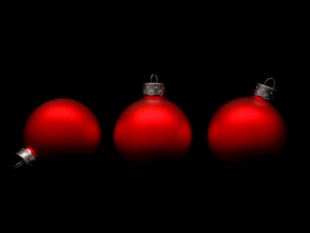 Studio shot close-up of three vintage red and matte traditional Christmas baubles with shadow on black background with copy space