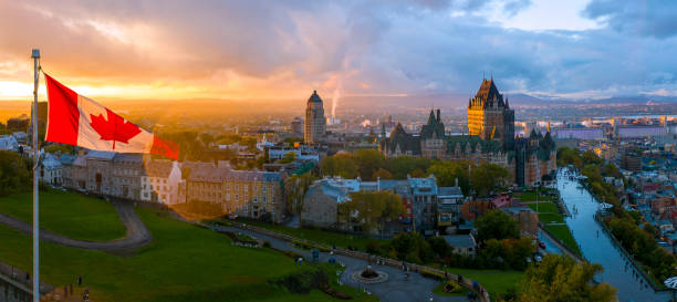 kanadische flagge weht bei sonnenuntergang über einer malerischen altstadt von québec - canadian flag fotos stock-fotos und bilder