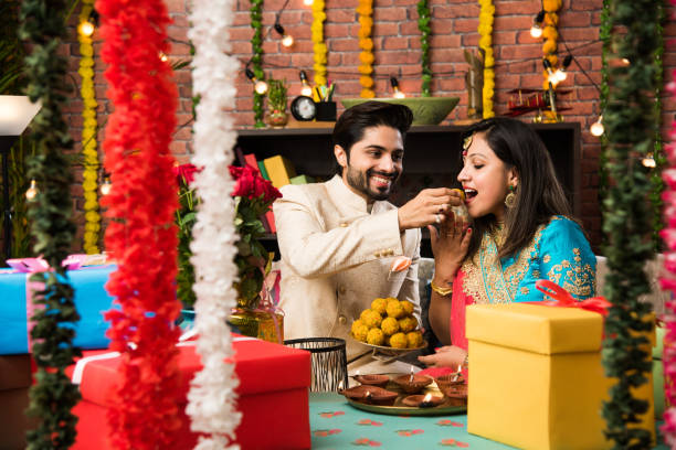 Indian smart couple eating sweet laddu on Diwali or anniversary, selective focus Indian smart couple eating sweet laddu on Diwali or anniversary, selective focus diwali stock pictures, royalty-free photos & images