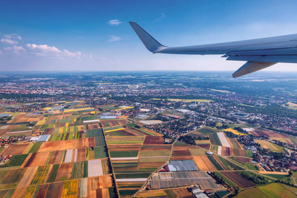 istock Airplane windows view above the earth on landmark down. View from an airplane window over a wing flying high above farmlands and fields. View from window of plane airplane flying. 1178974627
