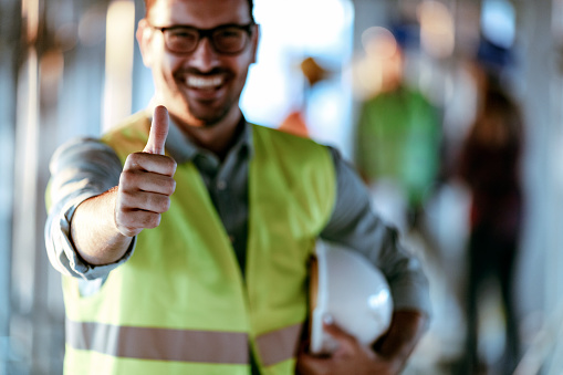 Construction worker gesturing thumbs up. Positive emotion, one construction worker showing hand with thumbs up, selective focus. Construction worker showing hand with thumb up.