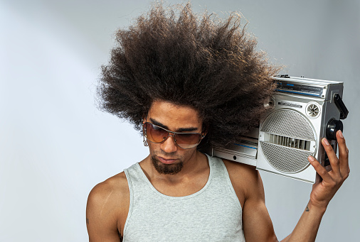 Man with big afro hair  listening to funky music on ghetto blaster, studio shot