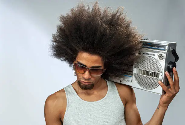Man with big afro hair  listening to funky music on ghetto blaster, studio shot