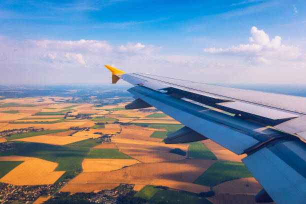 istock Airplane windows view above the earth on landmark down. View from an airplane window over a wing flying high above farmlands and fields. View from window of plane airplane flying. 1178984838