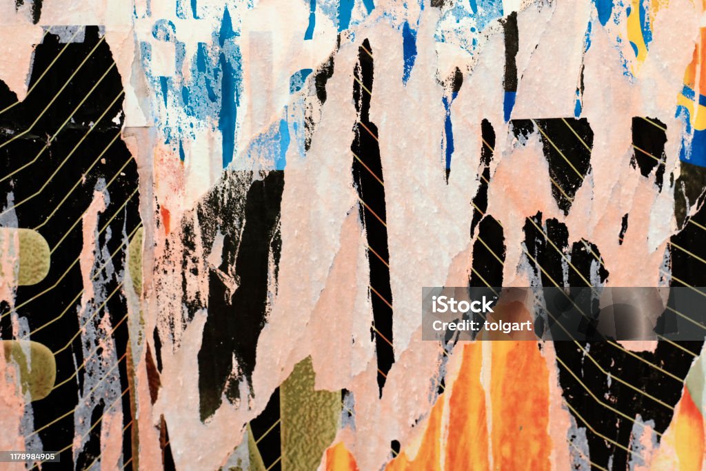 Pieces of torn paper peeling off wall used as billboard Torn Ripped Paper Poster Street Wall Surface. Grunge Rough Dirty Rust Background Newspaper Stock Photo