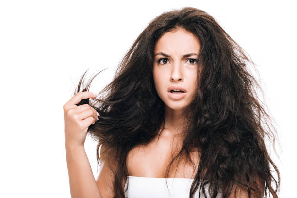 estresado morena hermosa mujer sosteniendo el pelo seco dañado aislado en blanco - despeinado fotografías e imágenes de stock