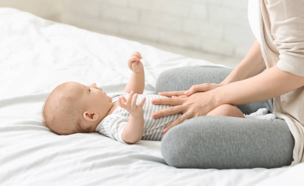 frau massiert bauch ihres sohnes vor kolikern - abdomen women massaging human hand stock-fotos und bilder