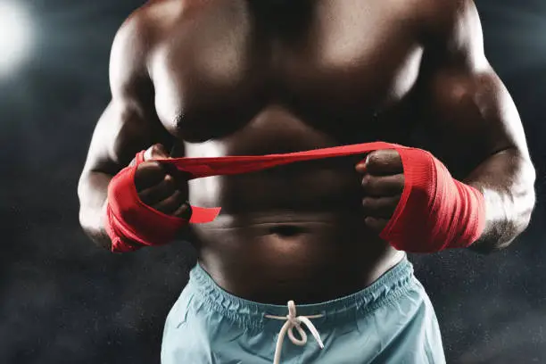 Photo of Close up of boxer pulling sports bandage, staying on ring