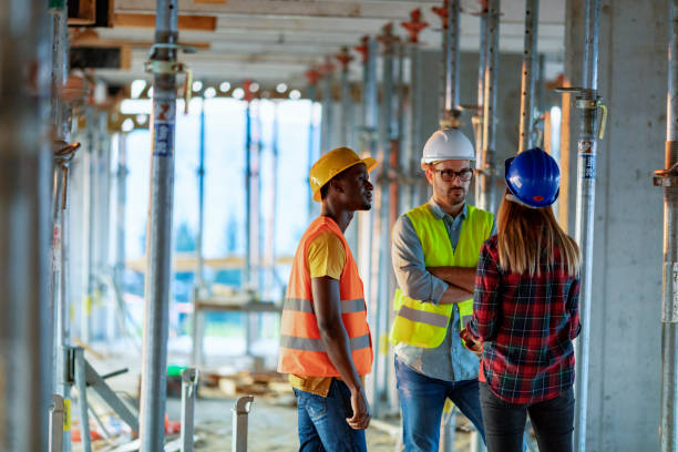 three multi-ethnic workers with hard hats - serious african ethnicity mid adult bright imagens e fotografias de stock