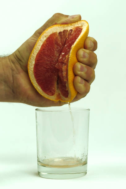 istock man squeezing half of juicy grapefruit to empty glass on white background, close up 1178988338